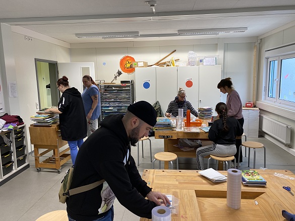 Mit Hilfe von Eltern werden die neuen Bücher mit Schutzfolie eingewickelt